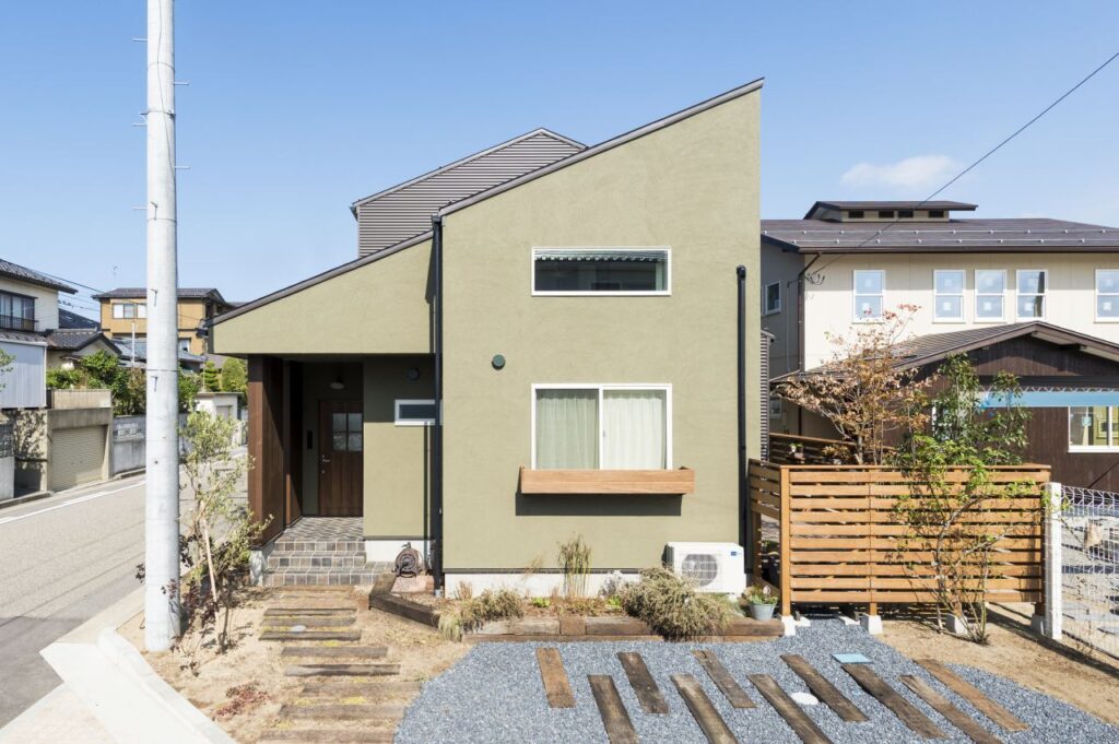 グリーンの塗り壁と木張りの外観