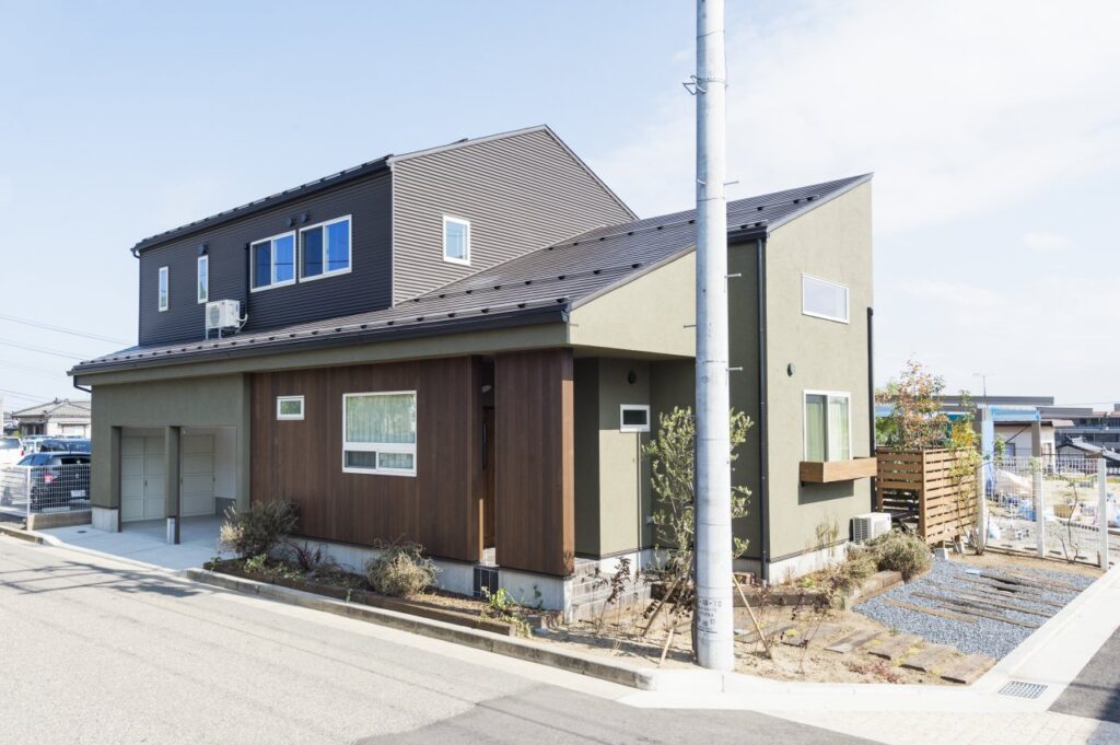 グリーンの塗り壁と木張りの外観