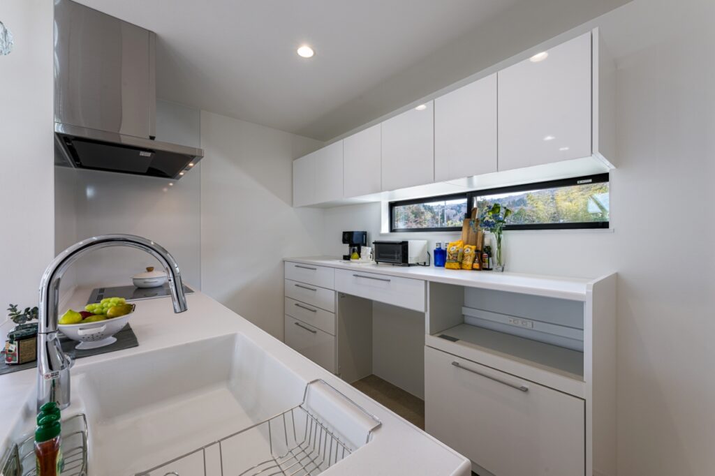 艶ありのホワイトでまとめ、手元の窓からは柔らかな光がこぼれるキッチン