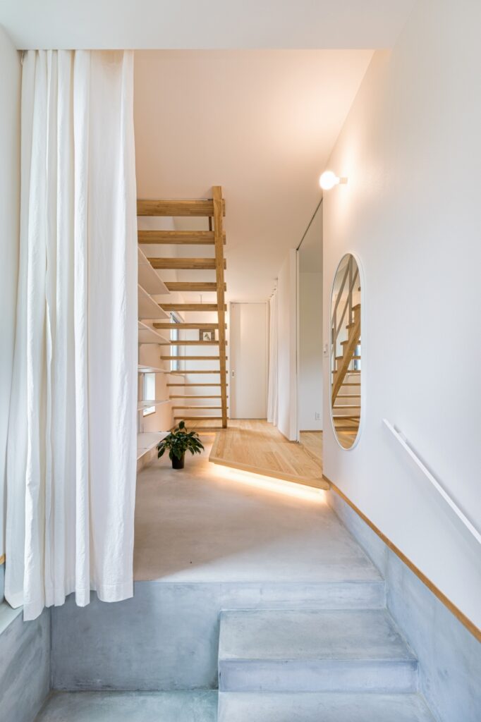 モルタルの床と間接照明で奥行きのある空間の玄関