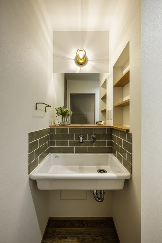 カーキのタイルとマリンランプが印象的な造作洗面