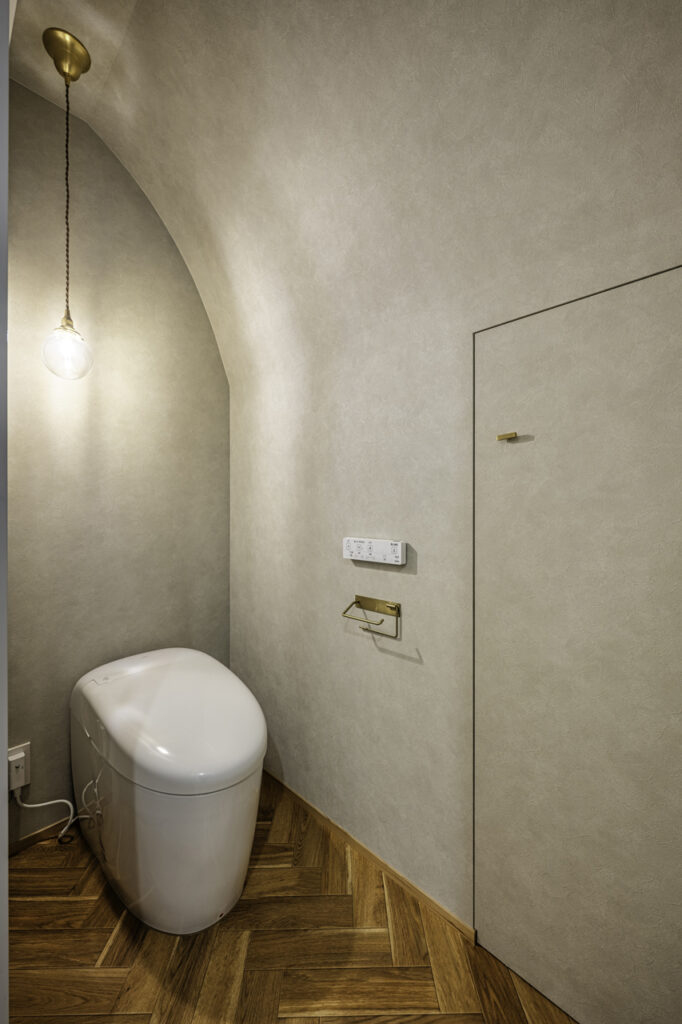 階段下収納とつながるアーチ天井のトイレ